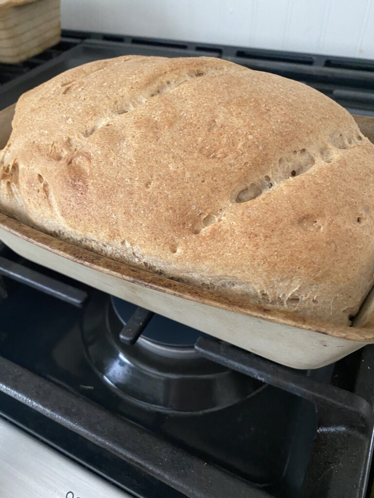 The Ultimate Easy Bread Machine Bread Recipe: Perfect for Beginners 3 Golden brown loaf of easy bread machine bread recipe freshly baked in a bread pan, resting on a stovetop, showcasing its rustic crust and homemade appeal.